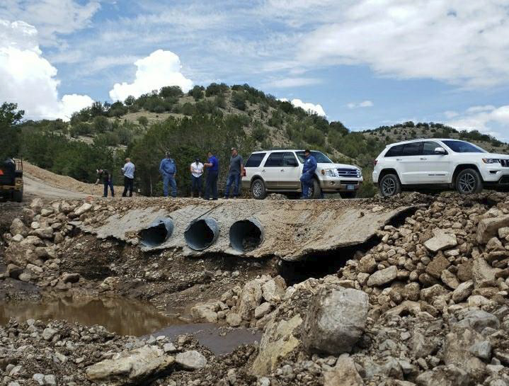 People and cars on road with drainage pipes visible